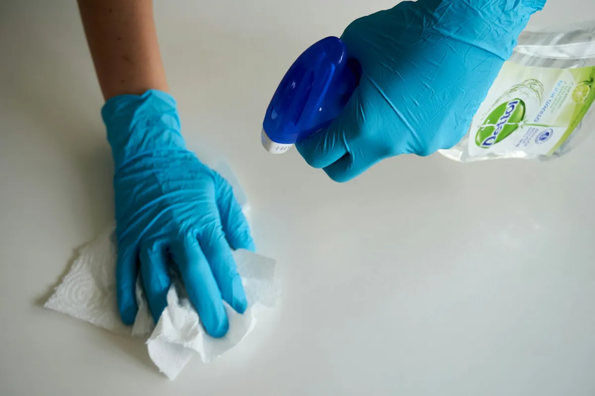A gloved hand wiping a pale surface with a cloth