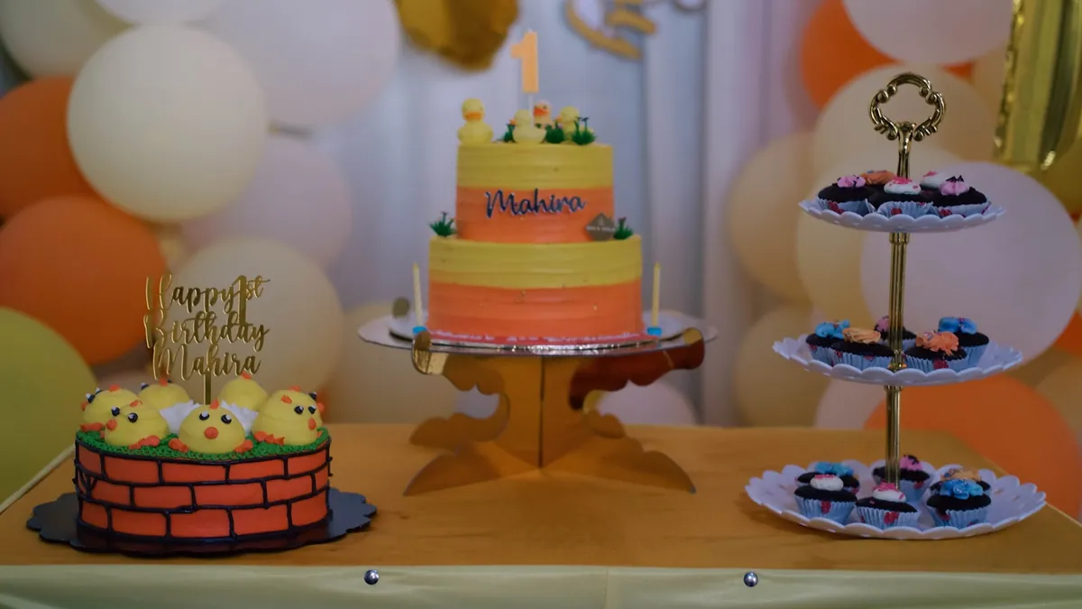 A tiered stand of small cakes beside a birthday cake