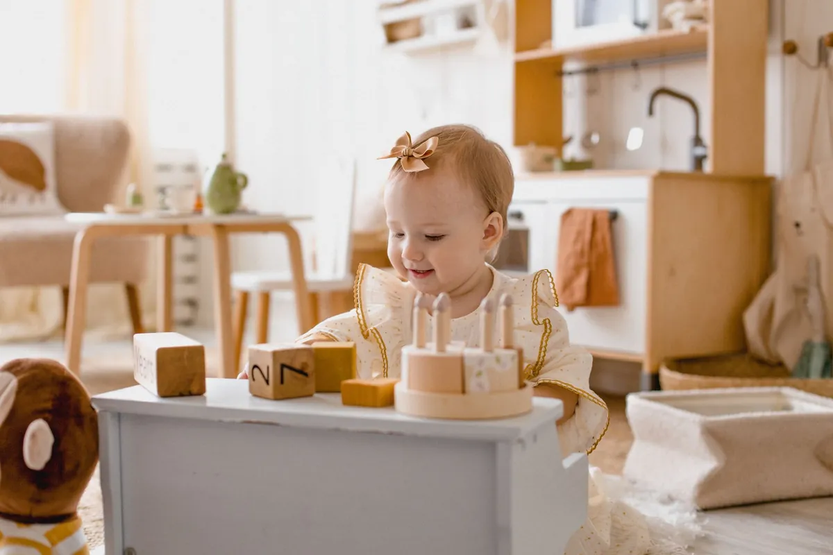 A toddler standing at a small wooden play kitchen