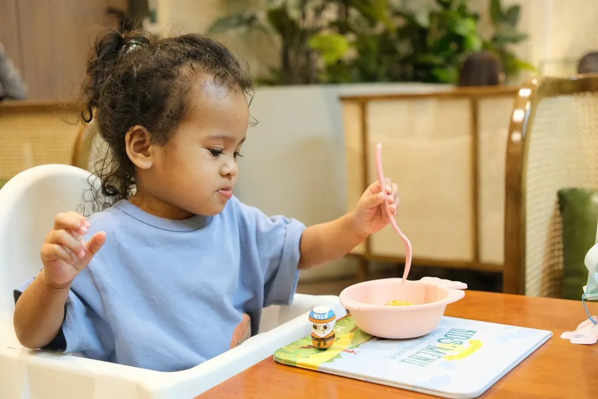 A toddler eating from a bowl in a high chair