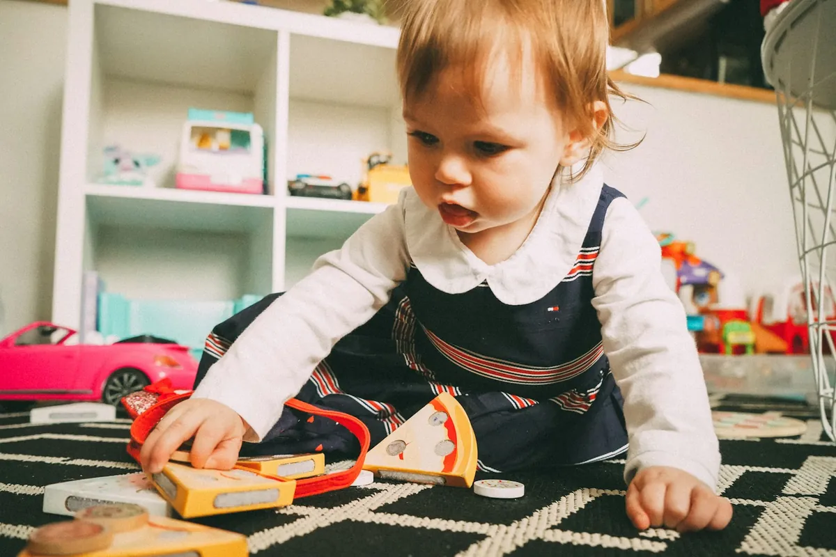 A toddler playing with toys on the floor of a playroom