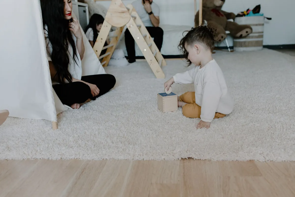 A toddler stacking wooden blocks on a soft rug