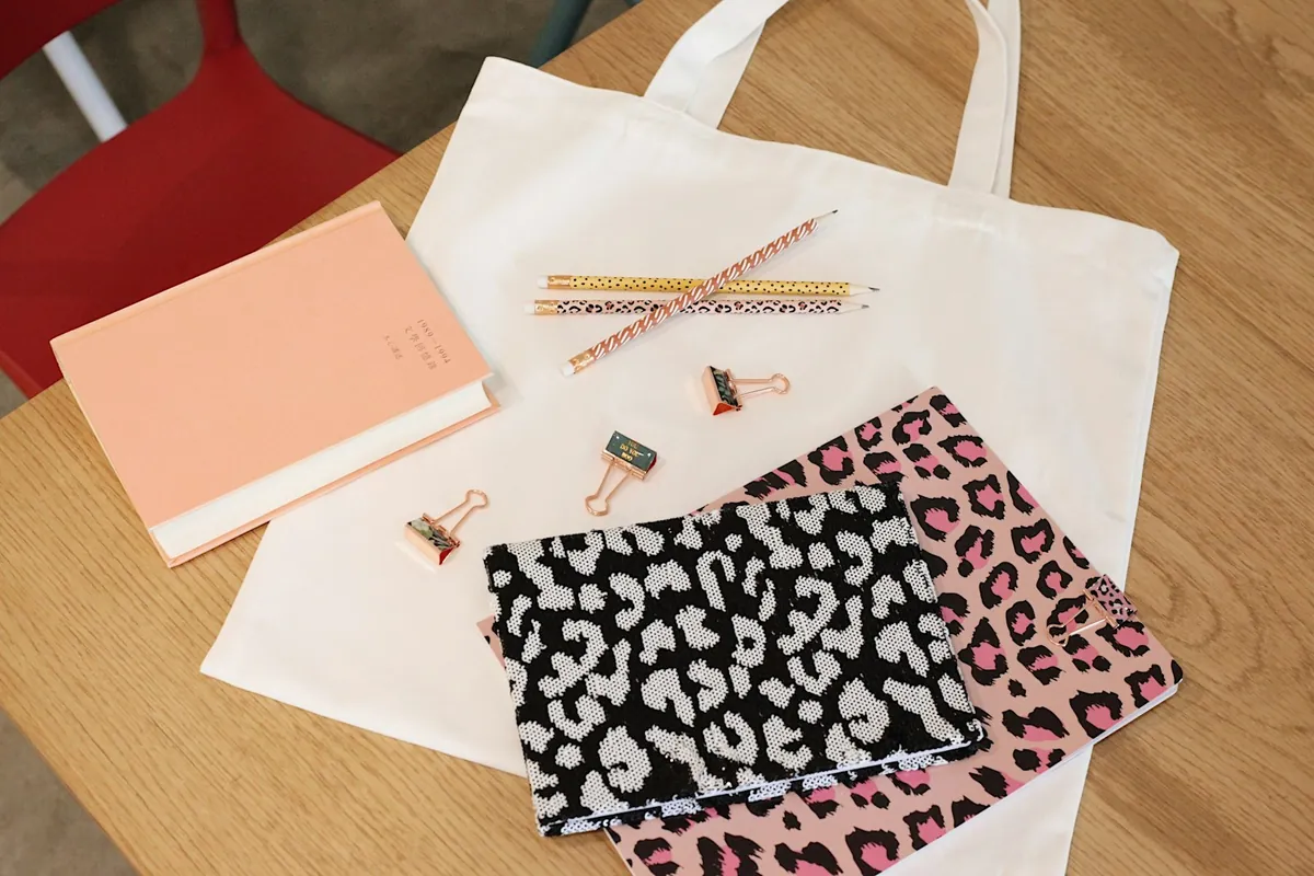 A tote bag laid out with a notebook and everyday essentials