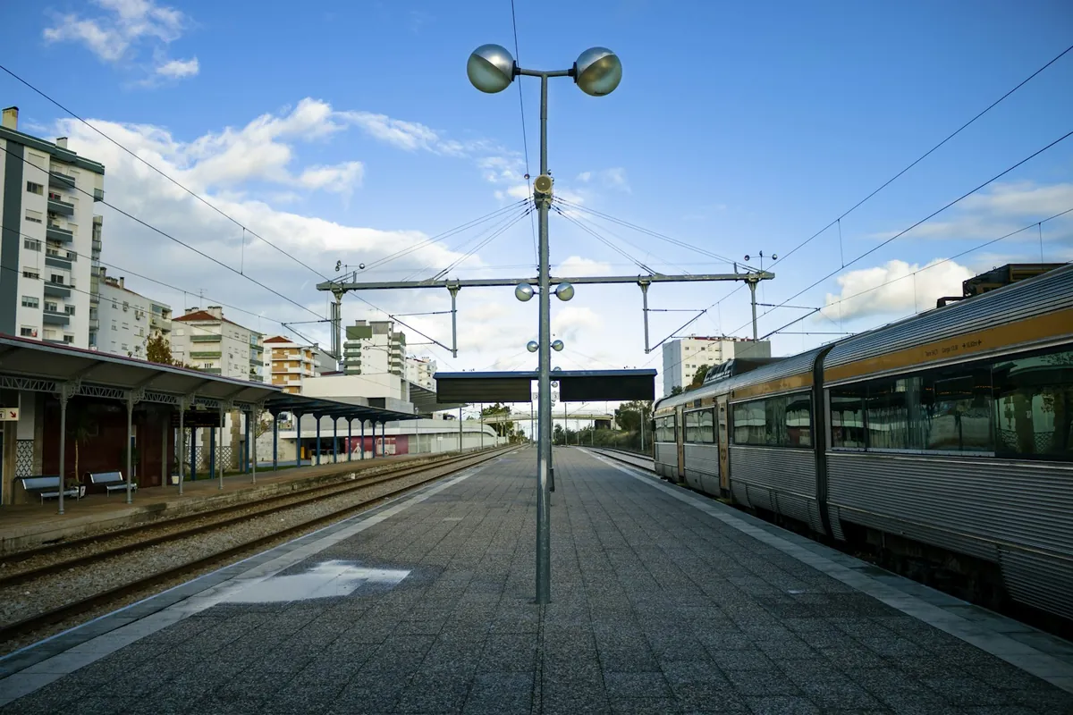 A train waiting at a suburban station under a blue sky