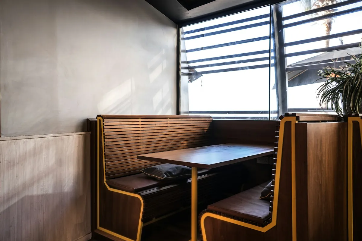 A wooden booth seat and table beside a window