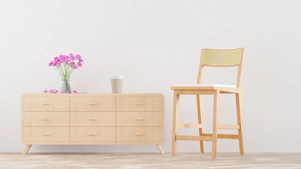 A plain wooden high chair standing beside a sideboard