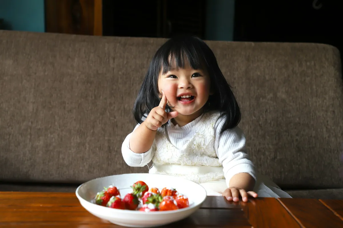 A young child eating from a bowl at a wooden table