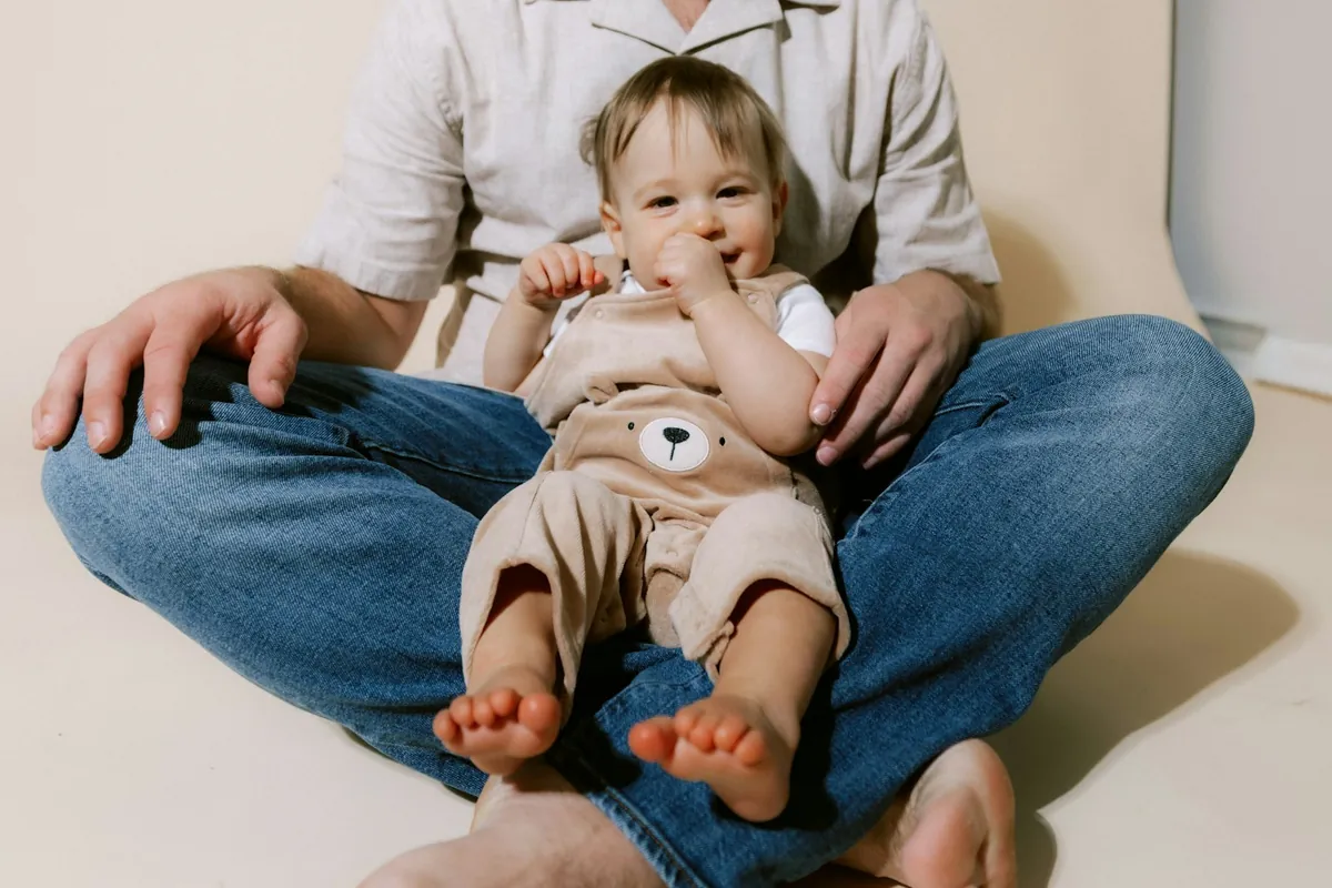 A young child sitting on an adult lap holding a toy
