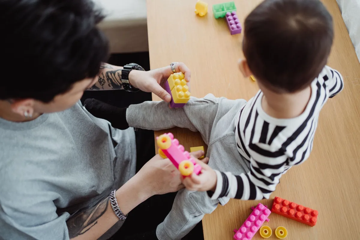 An adult and a small child building with plastic bricks
