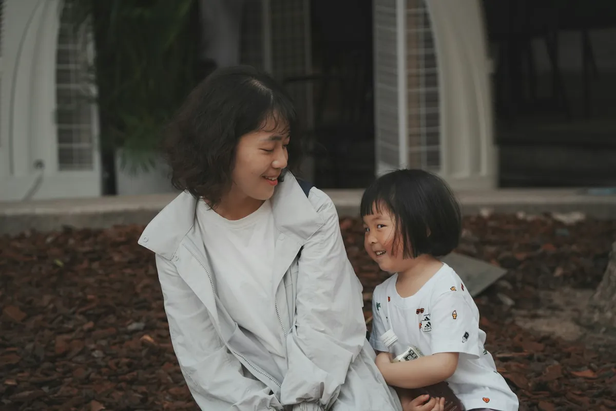 An adult and a young child sitting close together outdoors