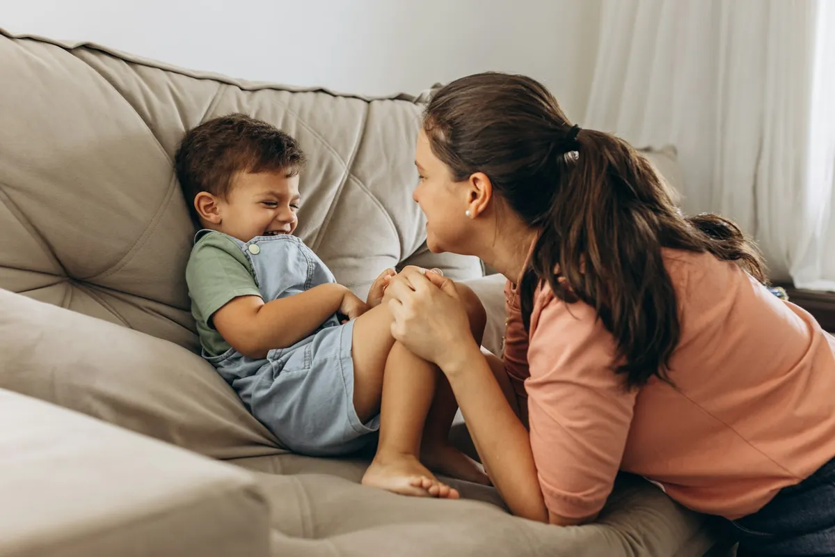 An adult and a young child talking together on a sofa