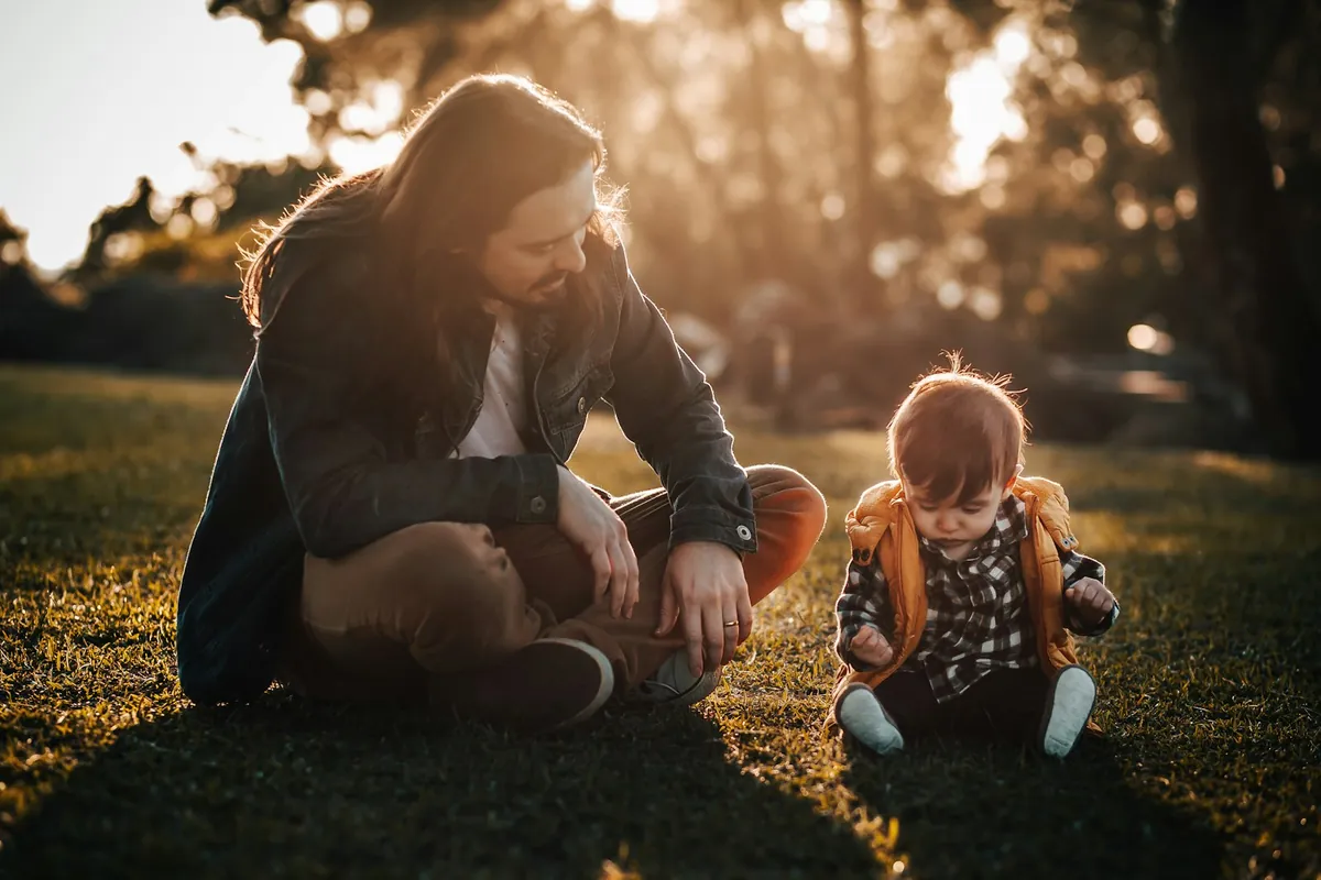 An adult crouching down to talk to a small child outdoors