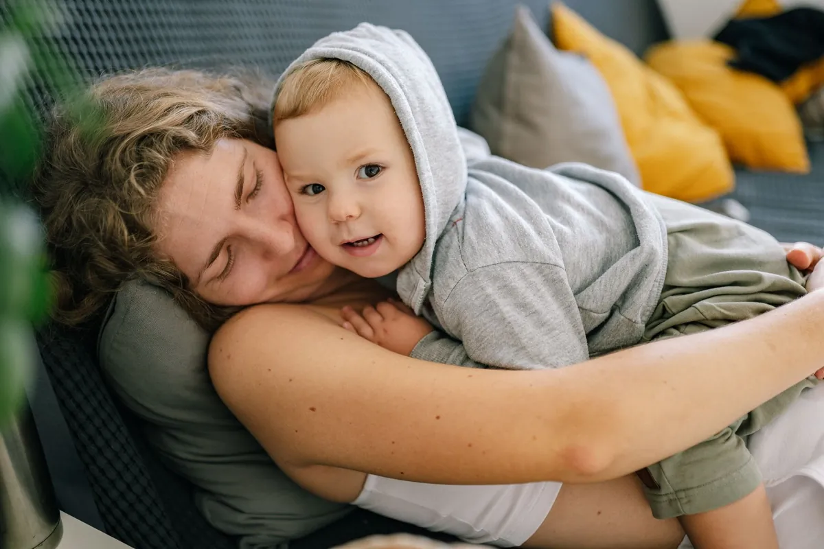 An adult cuddling a toddler on a sofa
