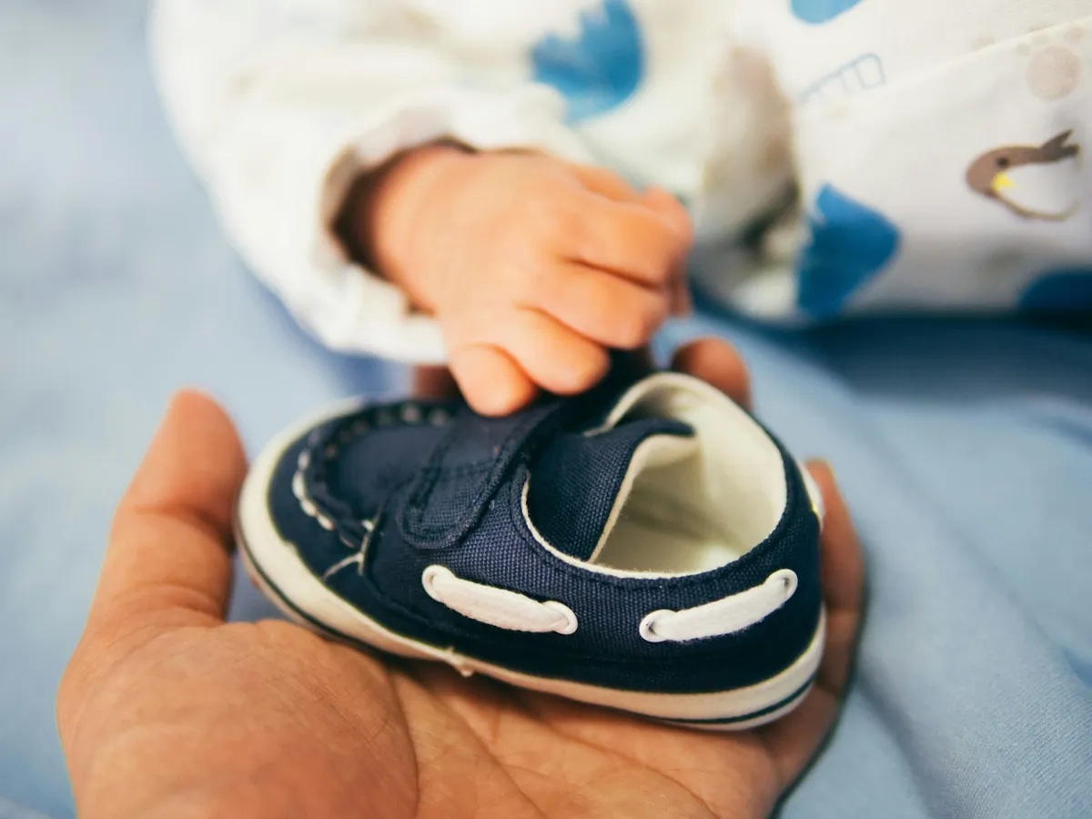 An adult holding a small child shoe