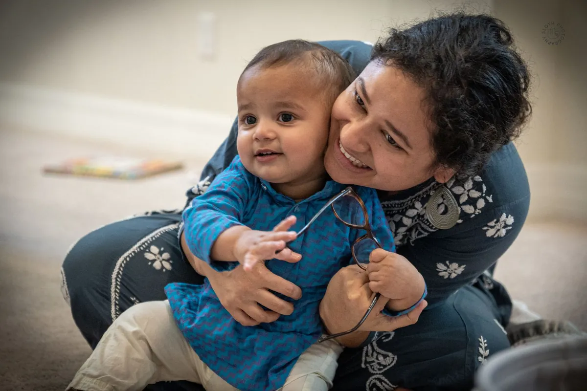 An adult sitting and holding a smiling baby