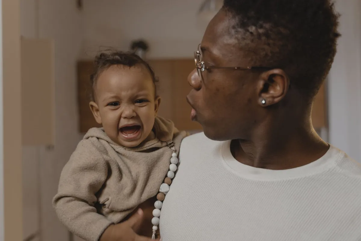 An adult holding a crying toddler in a living room