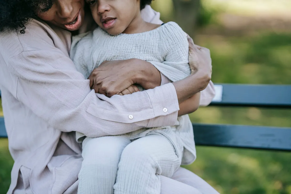 An adult hugging a child while sitting on a bench