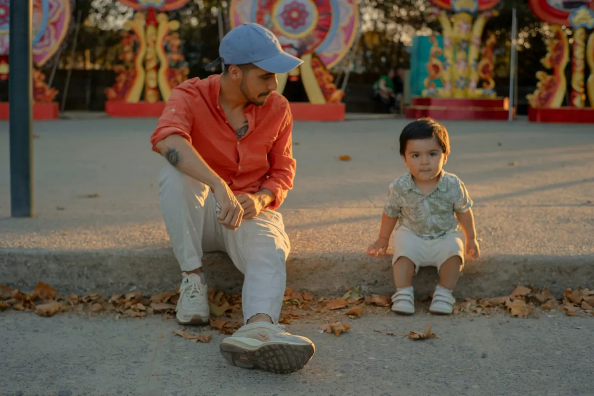 An adult kneeling on a path beside a toddler