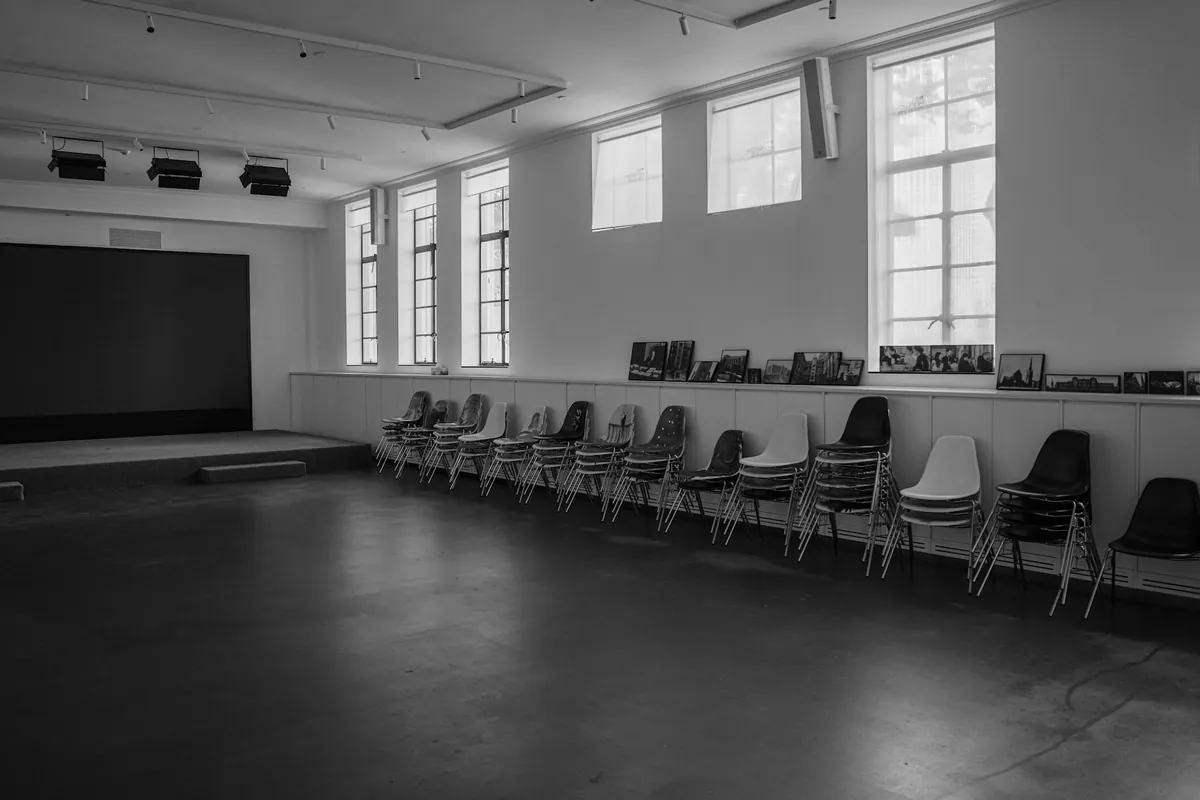 An empty hall with stacked chairs and daylight from high windows