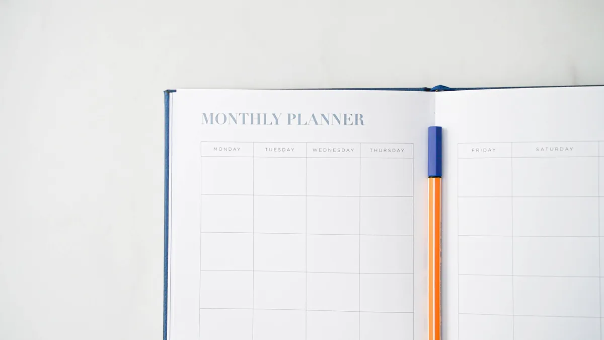 An open monthly planner with a pen resting on it