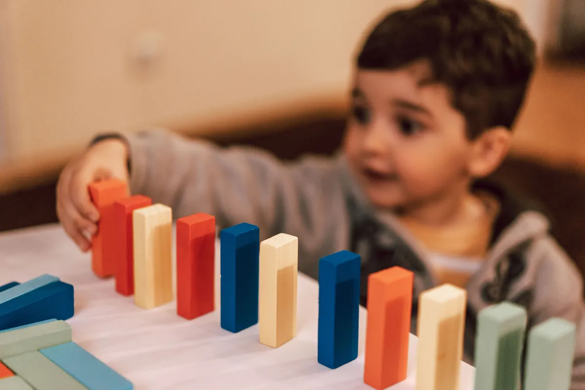 A young child playing with coloured wooden blocks