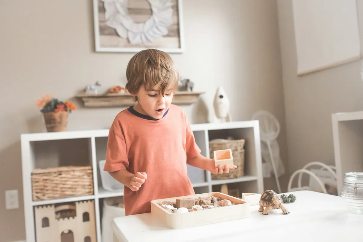 A young child playing with wooden toys beside a low shelf