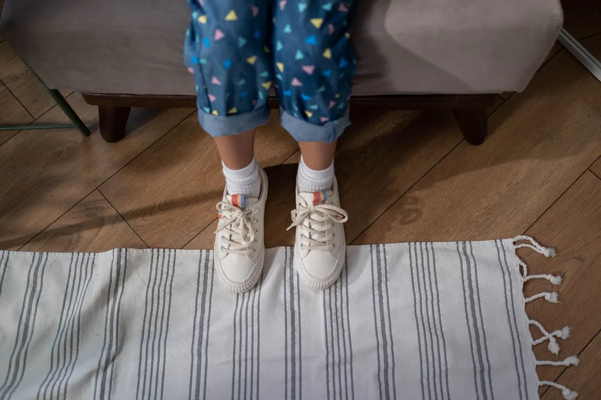 A child standing in socks on a rug at home