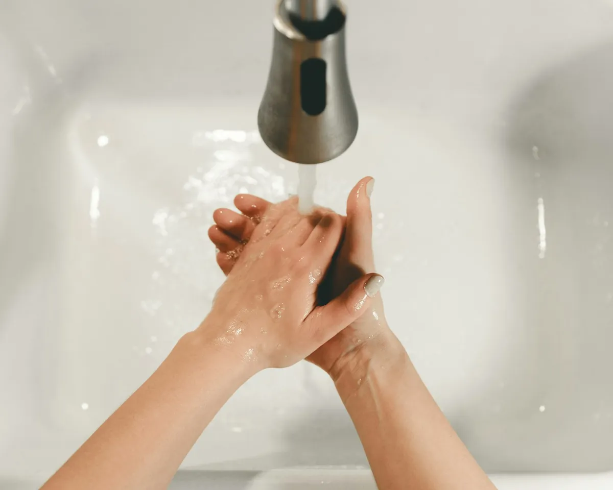 A child washing their hands under a running tap
