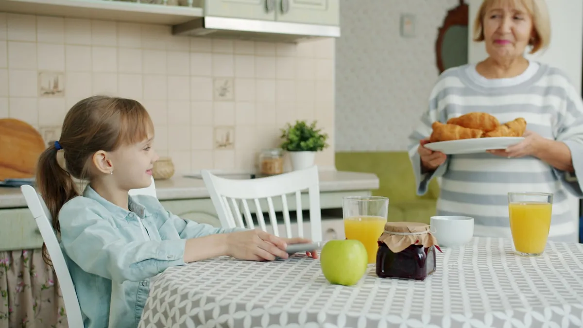 Two children seated at a kitchen table with breakfast