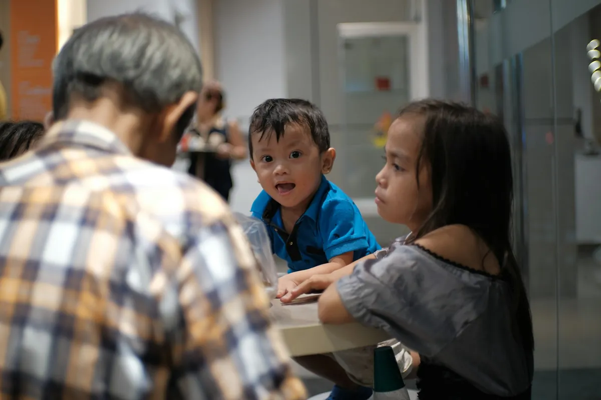 Two children eating at a cafe table with an adult