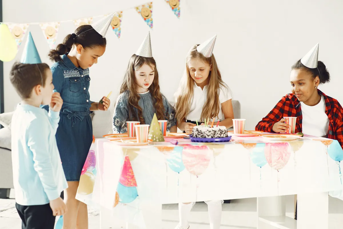 Children wearing party hats sitting around a decorated table
