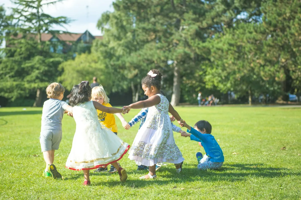 Children playing a circle game together on grass