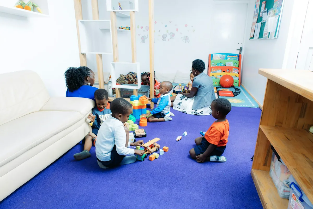Young children playing with toys on the floor of a bright play room