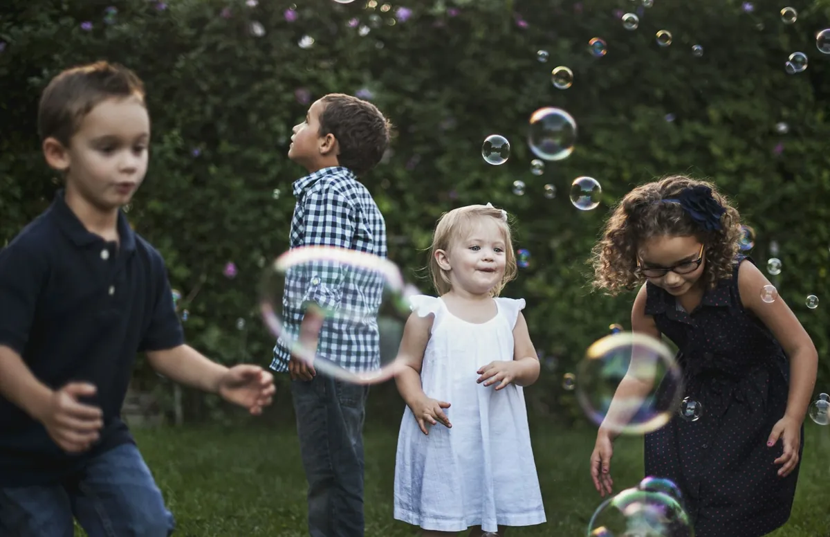 A group of young children playing with bubbles