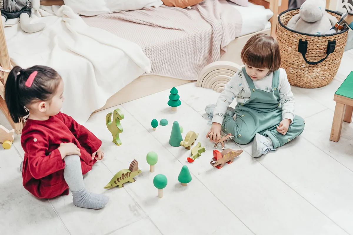 Two young children playing with small wooden figures indoors