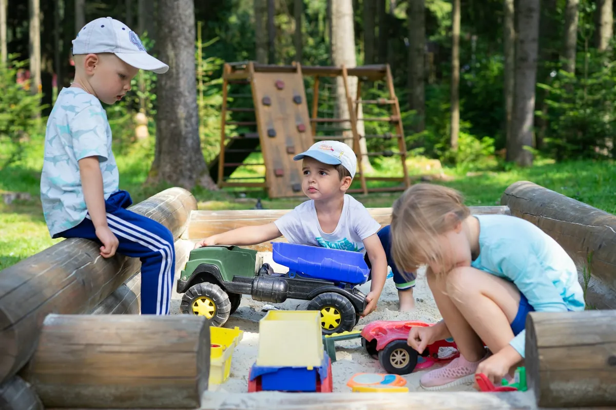 Young children playing side by side with toy trucks