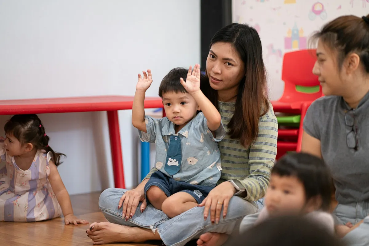 Young children raising their hands during a group session