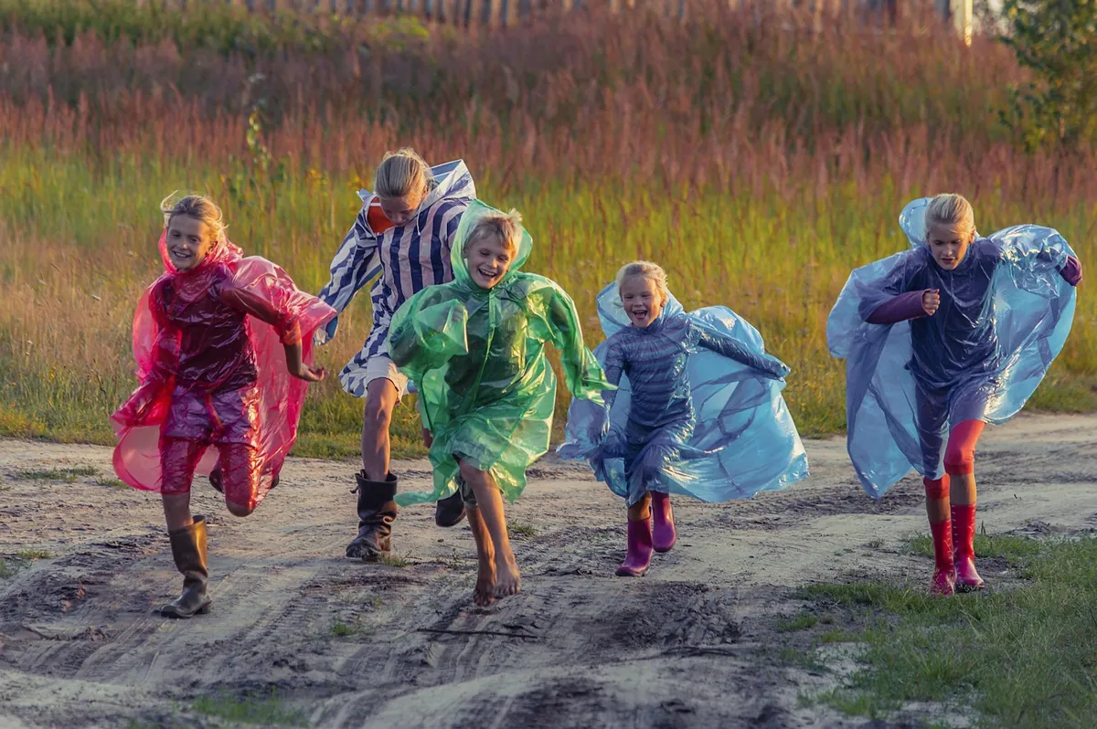 Children running together wearing colourful capes