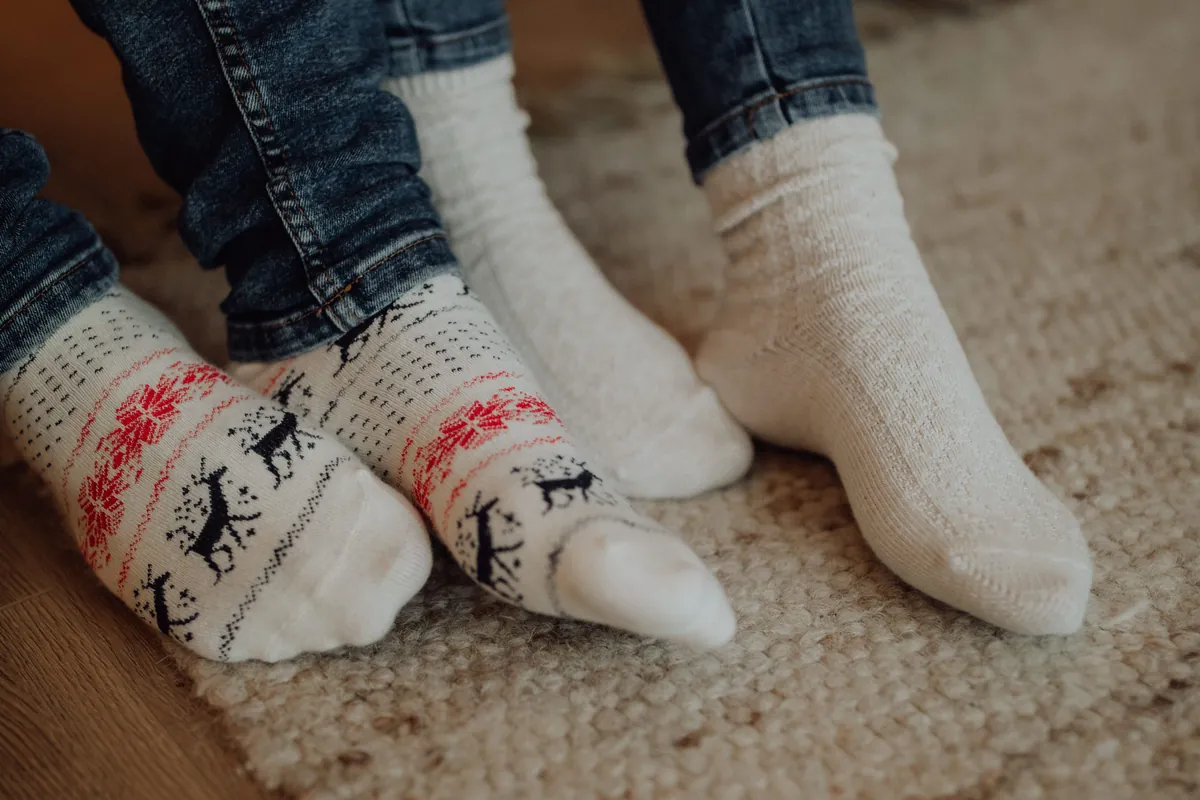 Two childrens feet in warm knitted socks on a rug