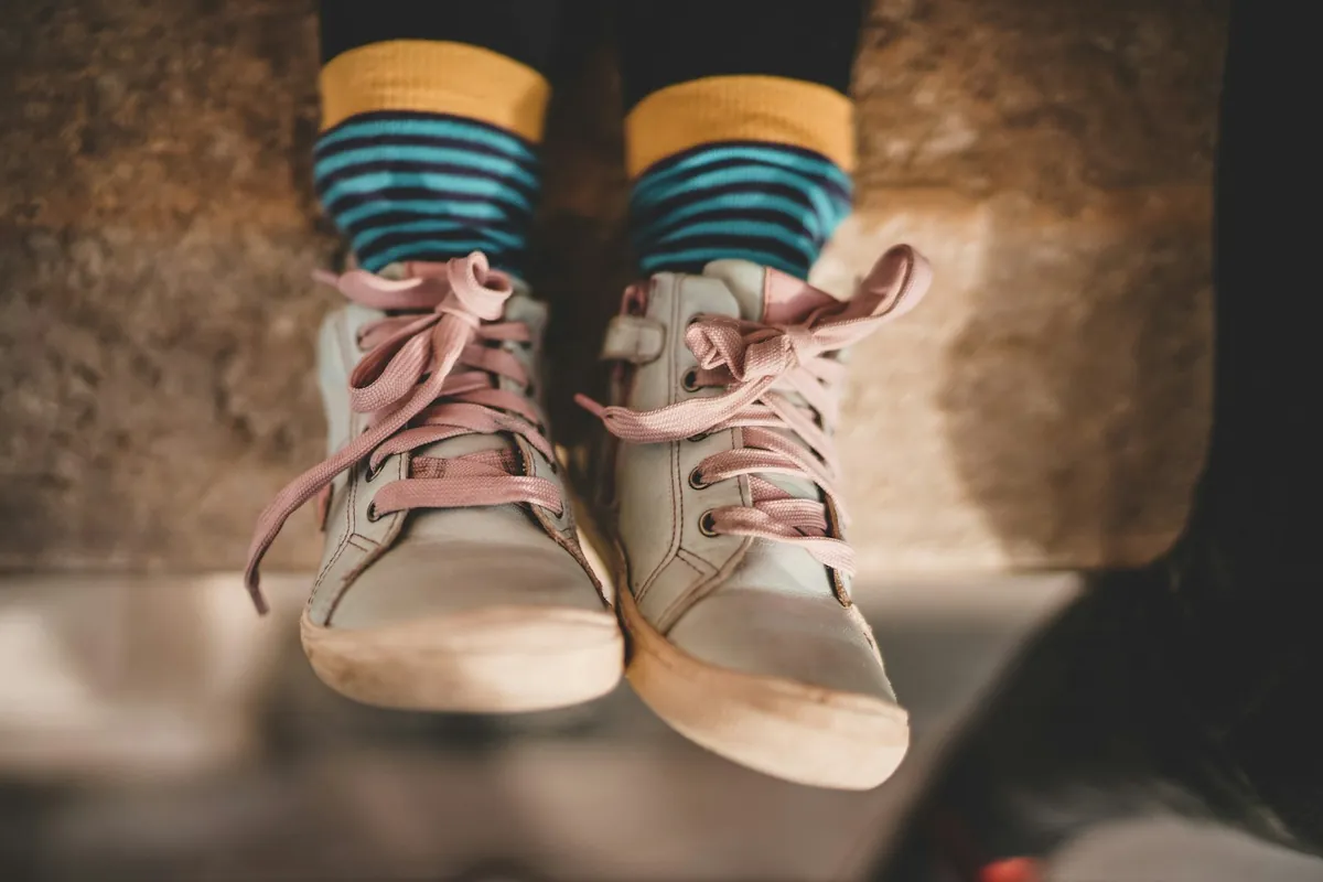 A child wearing striped socks and canvas shoes