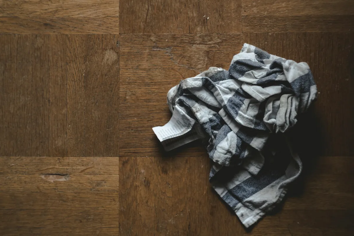 Folded cleaning cloths resting on a wooden floor