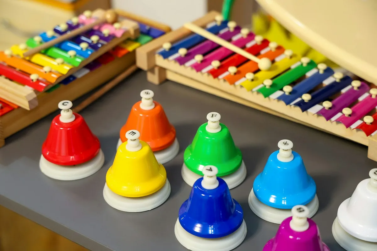 Coloured hand bells beside a wooden xylophone