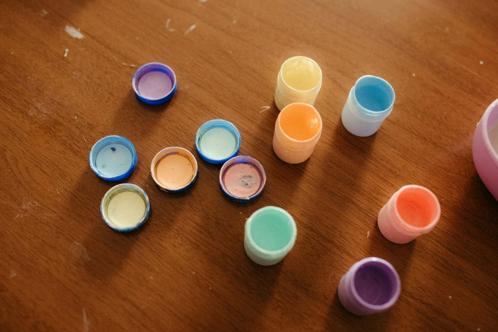 Small pots of coloured paint arranged on a wooden table