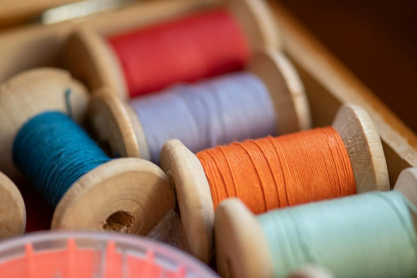 Wooden spools of coloured sewing thread in a box