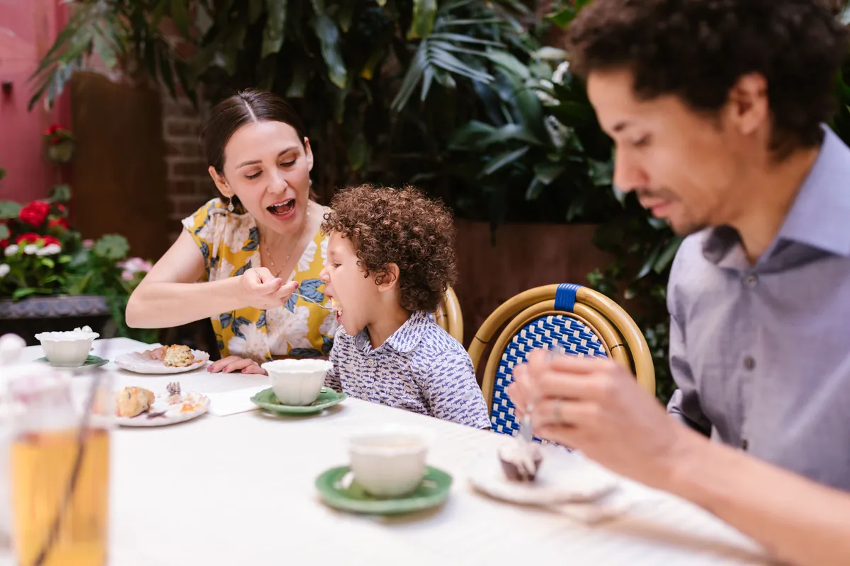 A family with a young child eating together at a cafe table