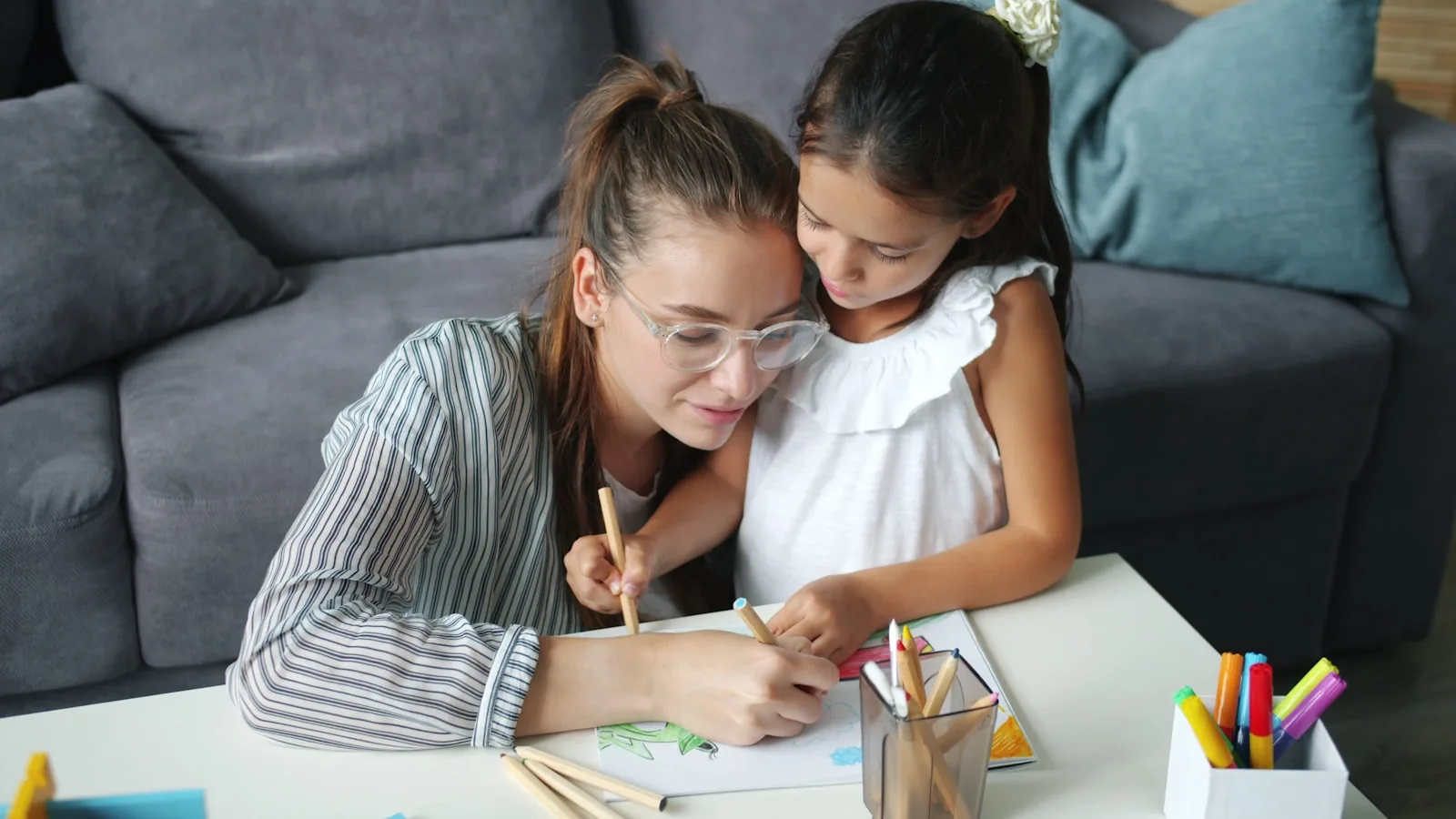 An adult and a child colouring together at a table