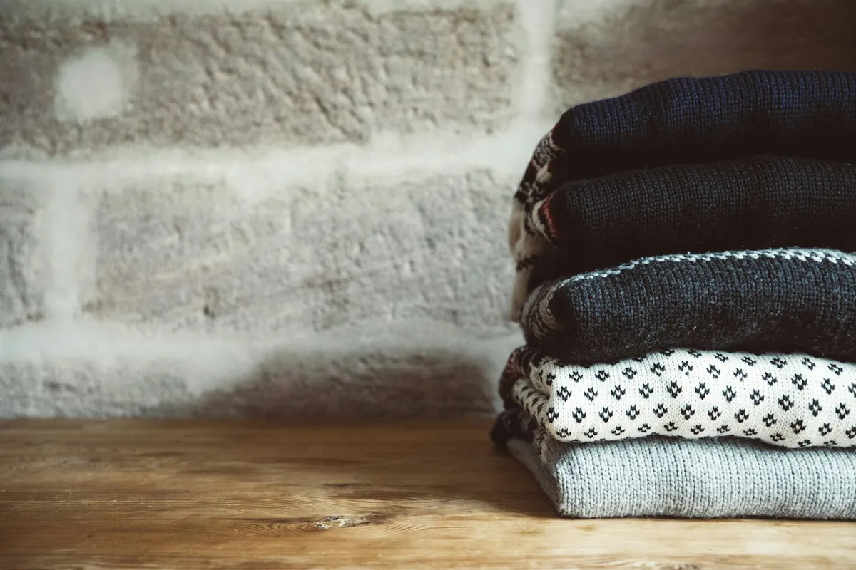 A neat stack of folded clothes against a brick wall