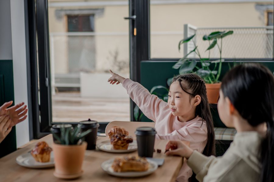 A parent and child sharing breakfast together at a cafe table