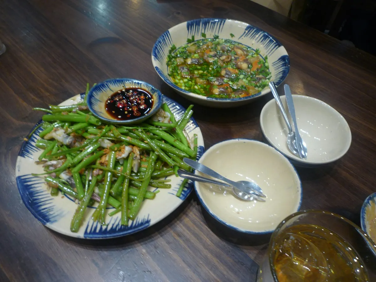 A plate of green beans beside small side bowls