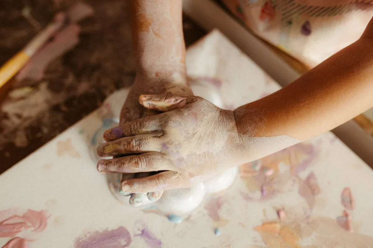 Two pairs of hands working with dough on a messy table